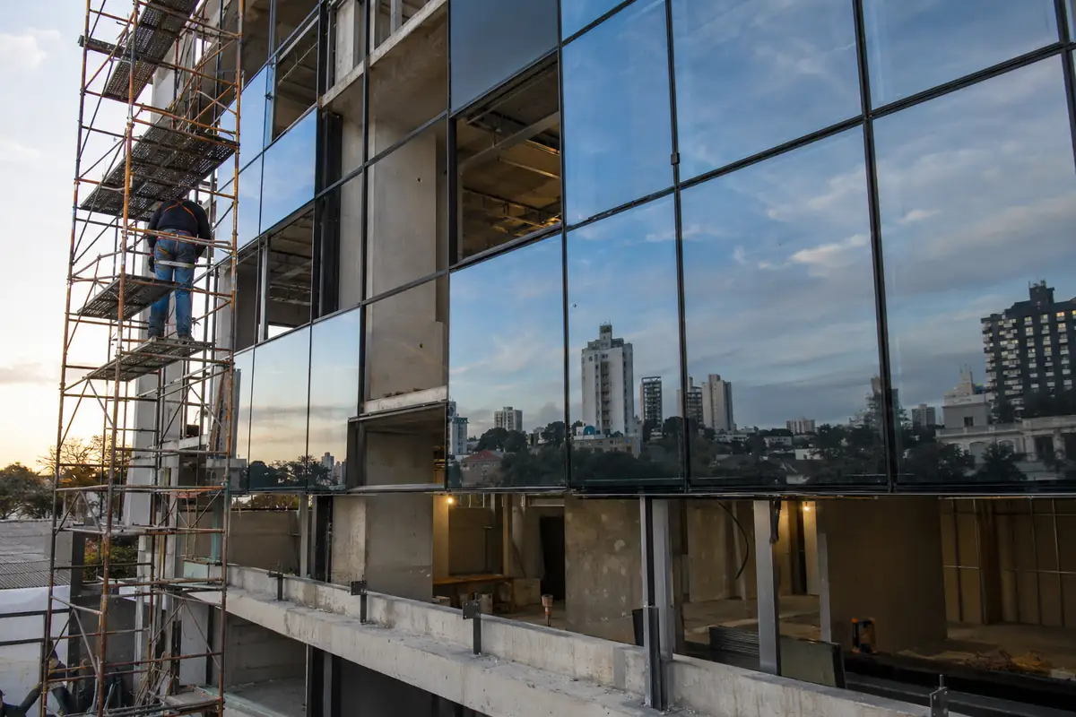 Fachada em pele de vidro sendo montada num prédio comercial, com andaime ao lado