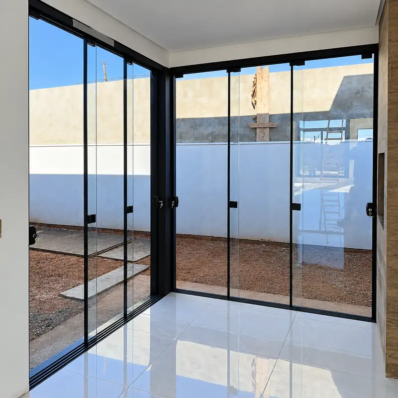 Portas de vidro temperado com perfil preto fechando uma área de piso claro